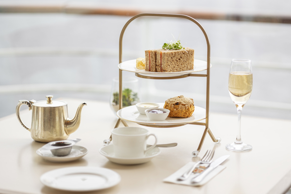 A table set with a cake stand, glass of fizz and pot of tea.